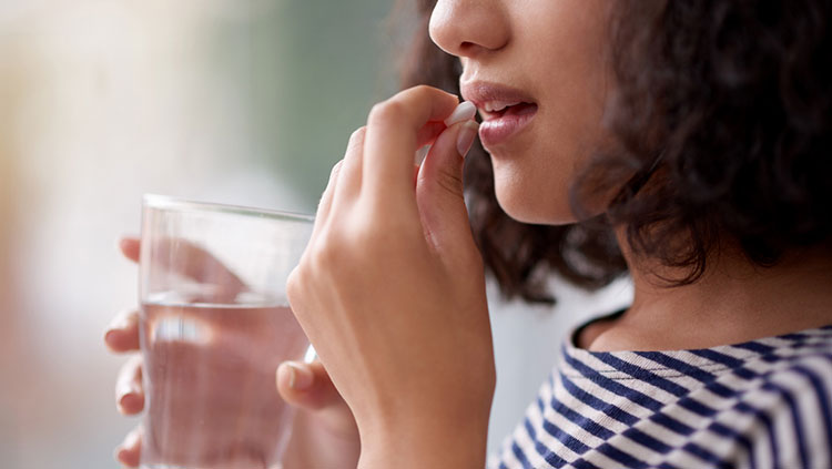 Woman taking a pill with glass of water