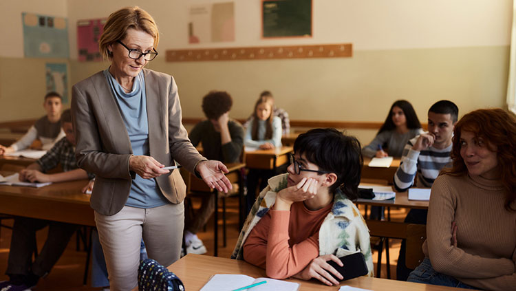 Teacher and student in classroom with a cell phone