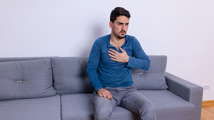 Man sitting on couch holding chest